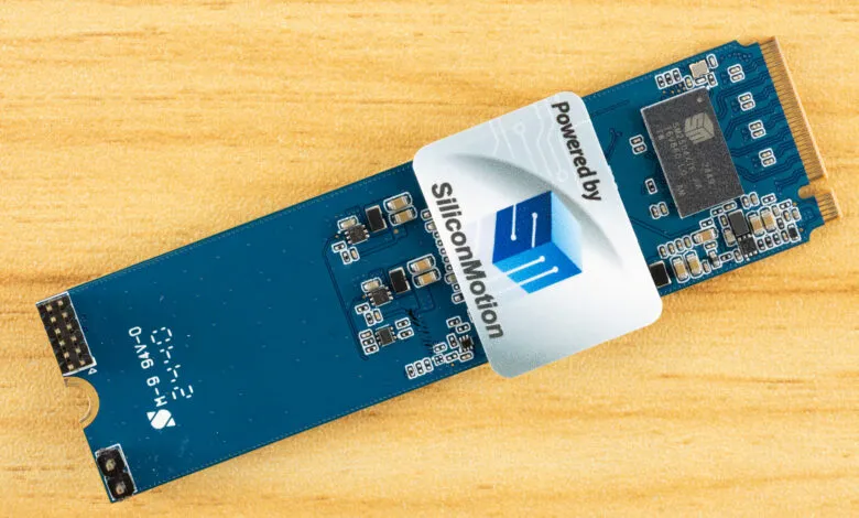 Close-up of a blue Silicon Motion powered SSD circuit board on a wood surface.