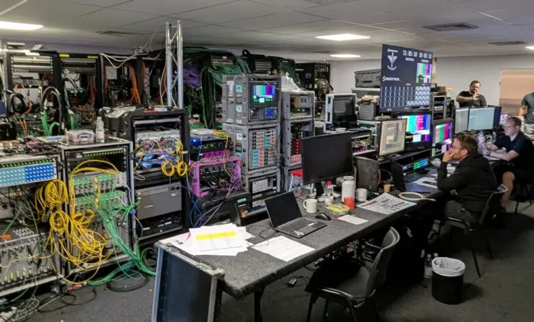 Broadcast control room with technicians monitoring screens and complex equipment.