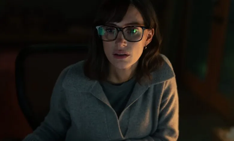 Woman with glasses looks intently at a computer screen, code reflected in her glasses.