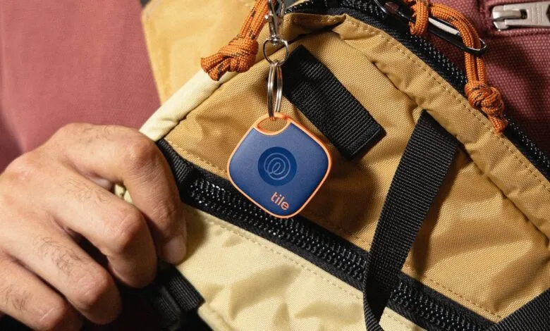 Close-up of a blue Tile tracker with an orange border attached to a backpack.