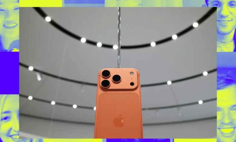 Close-up of a coral-colored iPhone's rear camera system, displayed against a modern interior backdrop.