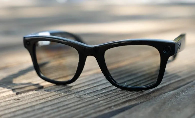 Close-up of Ray-Ban Meta smart glasses on a wooden surface. Sleek black frames with subtle camera lens.