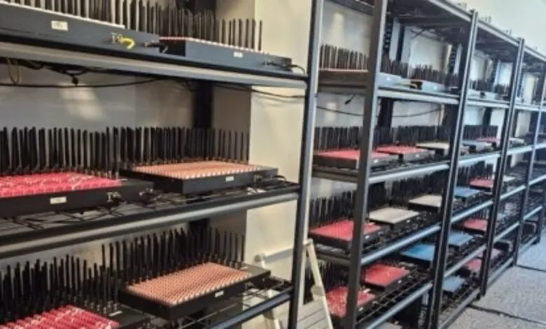 Rows of black devices with numerous antennas, arranged on metal shelves in a server room.