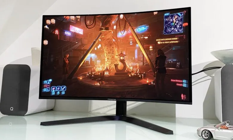 Cyberpunk video game scene displayed on a curved Predator monitor, showing a nighttime urban setting with candles and a central structure.