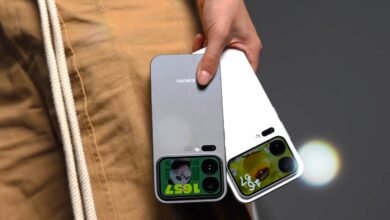 Two smartphones, one silver and one white, held by a person wearing tan pants.