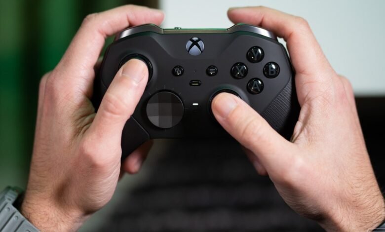 Close-up of hands holding a black Xbox Elite Series 2 controller, pressing buttons.