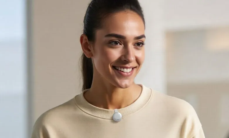 Smiling woman wearing a small, round, white device on her collar.