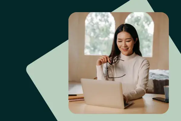 Smiling woman works on laptop in bright home office.