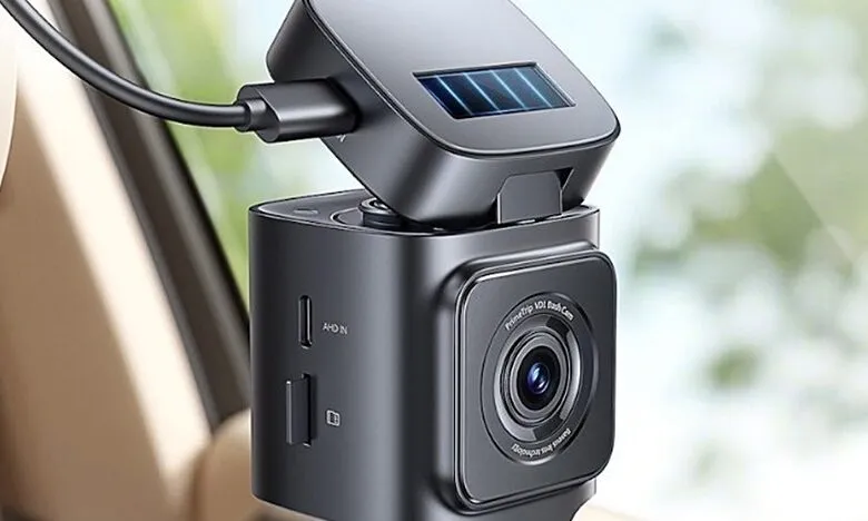 Compact black dashcam with solar panel attachment, mounted in a car. Features visible ports and lens.