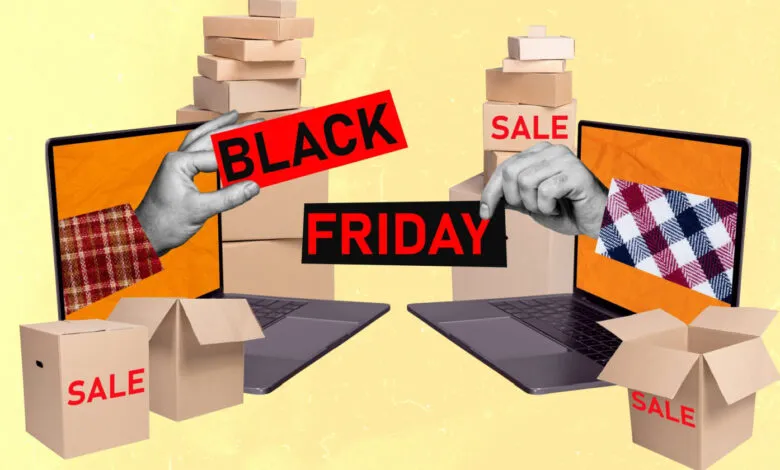 Hands holding Black Friday sale signs emerging from laptops surrounded by boxes.