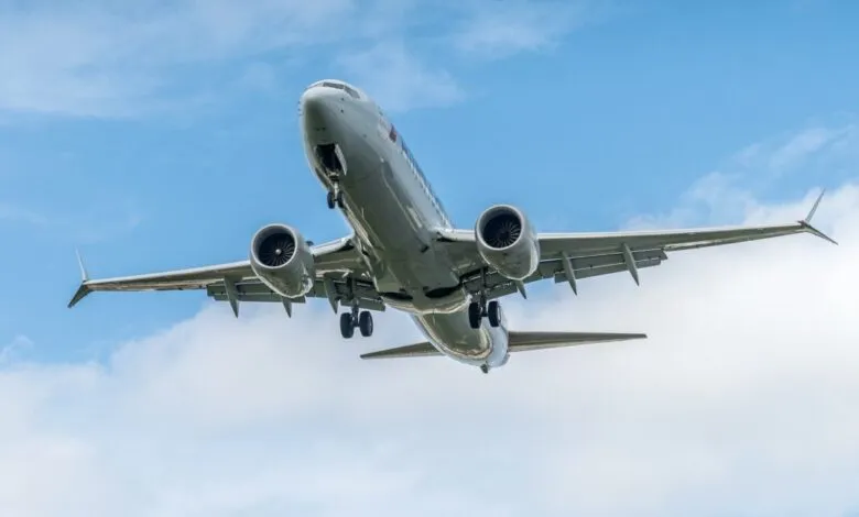 American Airlines Boeing 737 Max 8 airplane on approach, landing gear down, against a partly cloudy sky.