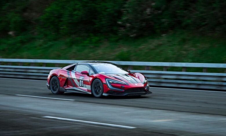 Red BYD Yangwang U9 supercar driving on a race track with blurred background.