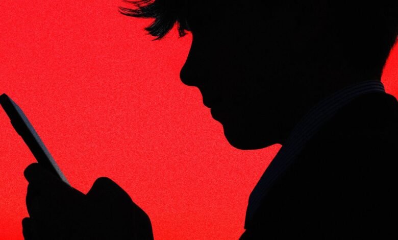 Silhouette of a person's head and hand holding a smartphone against a vibrant red background.