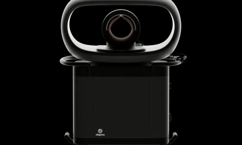 Modern medical device, dark gray, on wheels, with a curved top section.