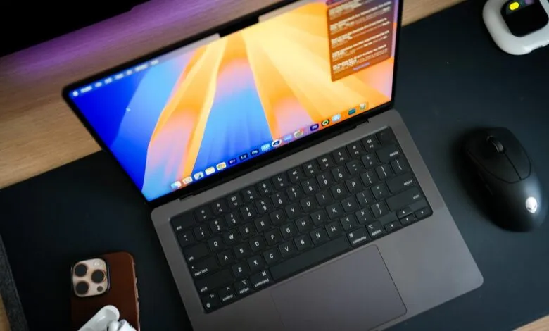 Modern workspace featuring a MacBook laptop with a vibrant screen, wireless mouse, and iPhone.