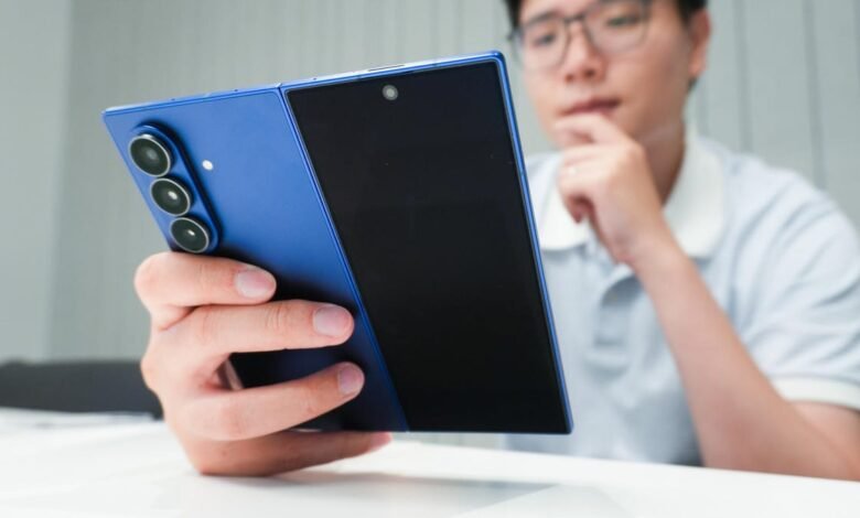 Person holding a blue foldable smartphone, examining its camera array.
