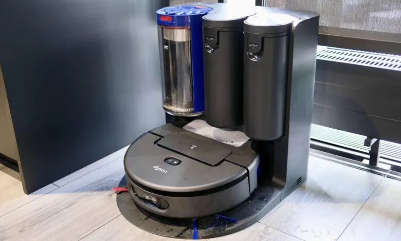 Dyson robot vacuum with self-emptying station. Dark gray robot, blue and black containers.