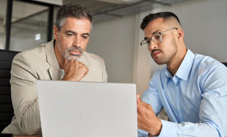Two businessmen review data on a laptop, collaborating intently.