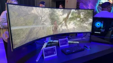 Curved gaming monitor displaying a fantasy game scene, alongside a gaming PC and keyboard.