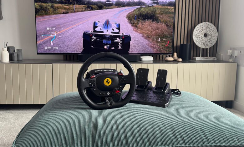 Thrustmaster racing wheel and pedals set up in front of a TV displaying a racing game.