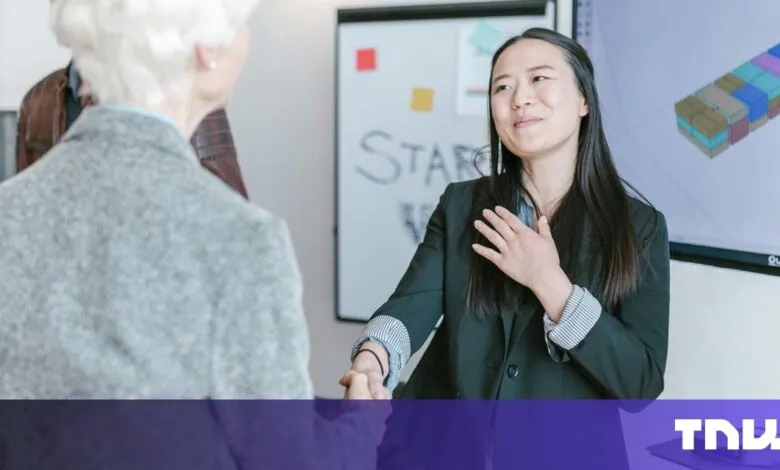 Businesswoman shakes hands, expressing gratitude. A presentation screen shows a 3D model.