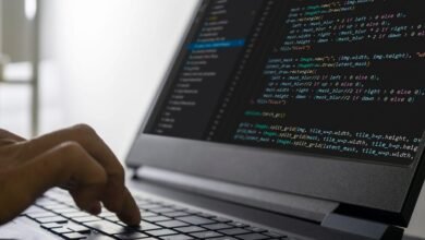 Close-up of hands typing code on a laptop, showcasing lines of programming code on the screen.
