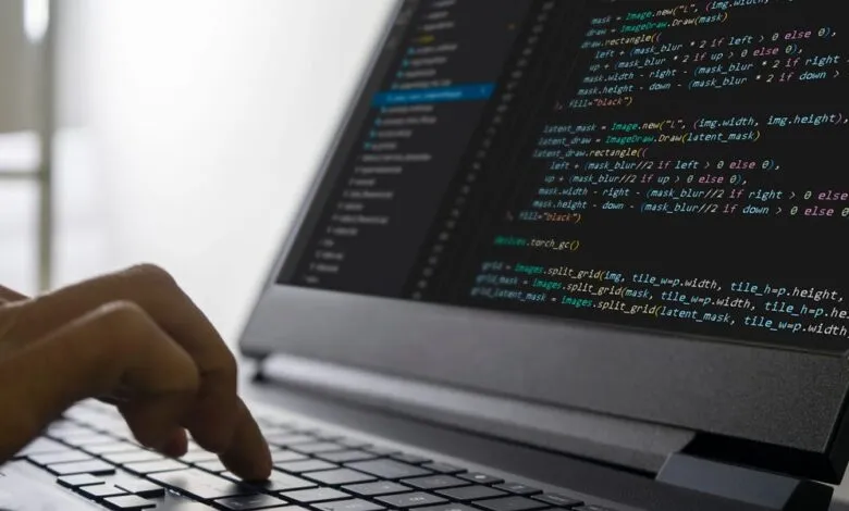 Close-up of hands typing code on a laptop, showcasing lines of programming code on the screen.