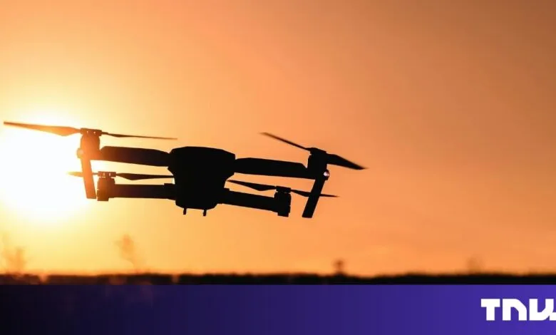 Silhouette of a drone flying against a vibrant sunset.