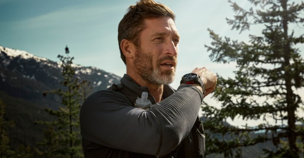 Man checks smartwatch during hike in mountains.