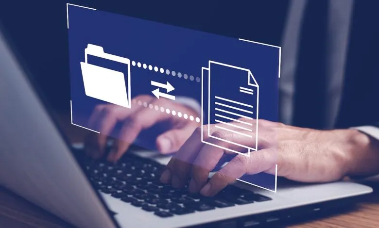 Hands typing on a laptop with a digital graphic showing file transfer.