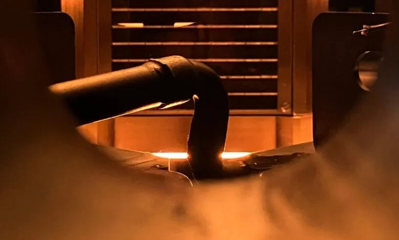 Close-up of a metal pipe glowing orange inside an industrial furnace.