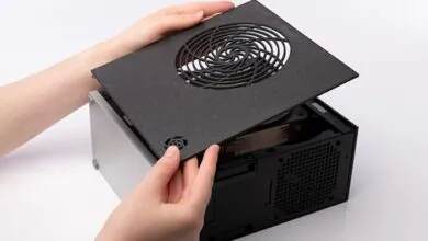 Hands installing a 3D-printed fan grill on a small, black computer case.