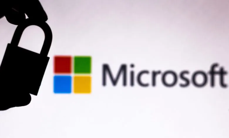 Silhouette of a hand holding a padlock in front of the Microsoft logo, symbolizing security.