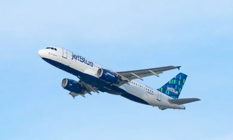 JetBlue Airbus A320 ascending against a clear blue sky.