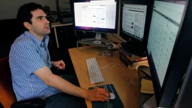 Man works at computer with two monitors, focused on screen.