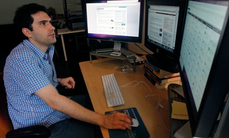 Man works at computer with two monitors, focused on screen.