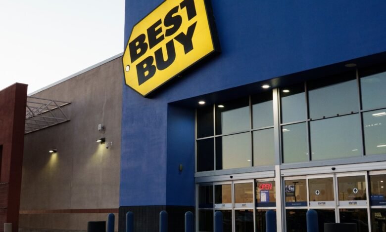 Best Buy store entrance at dusk, featuring a large yellow and black logo on a blue building.