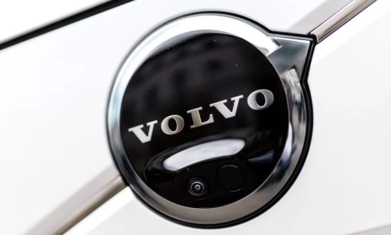 Close-up of a Volvo car's charging port, featuring the Volvo logo and a camera.