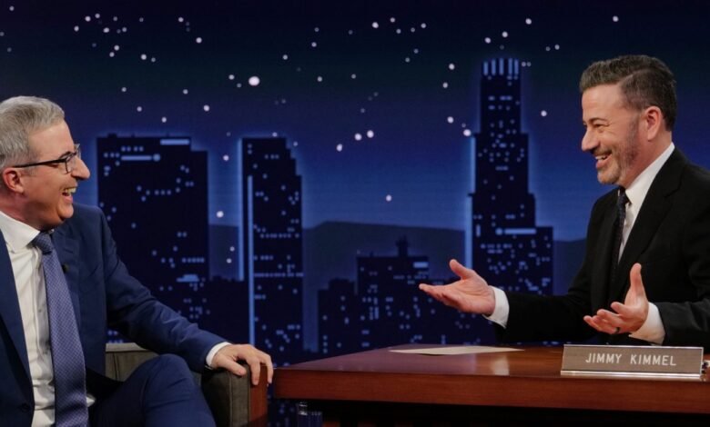 Stephen Colbert and Jimmy Kimmel laughing together on a talk show set.