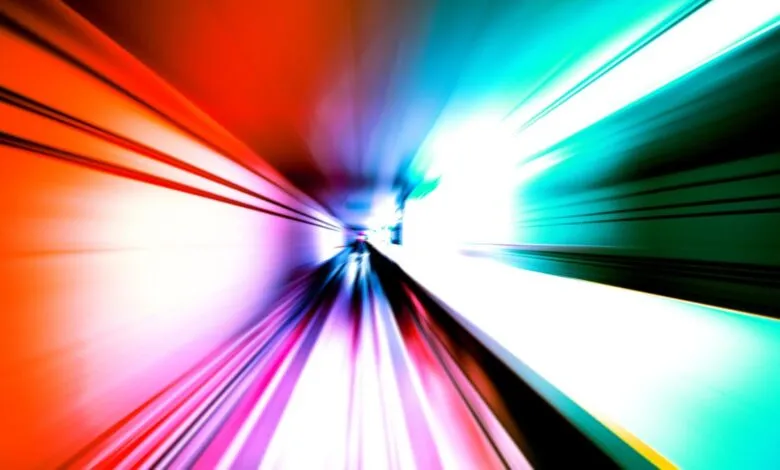 Abstract streaks of red, pink, and teal light blur into a vanishing point, suggesting rapid movement.