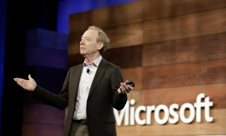 Steve Ballmer speaking on stage with Microsoft logo behind him.