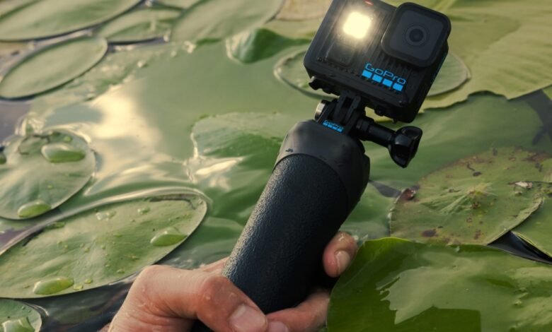 GoPro camera mounted on a selfie stick, held above lily pads in a pond.