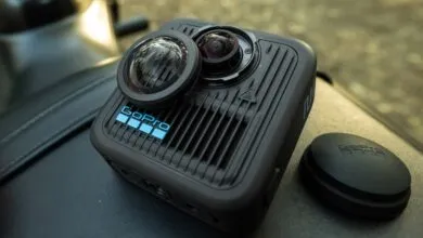 GoPro Max 2 360° camera with lens cap and mount, resting on a black surface.