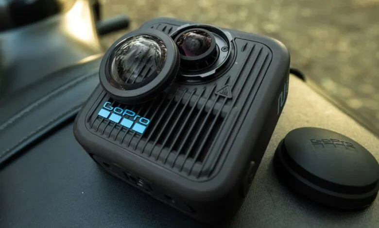 GoPro Max 2 360° camera with lens cap and mount, resting on a black surface.