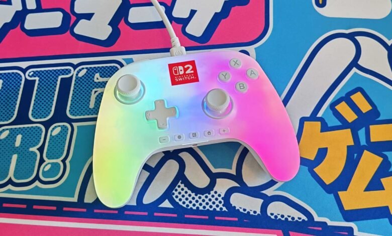 White Nintendo Switch controller with rainbow backlight on a colorful surface.