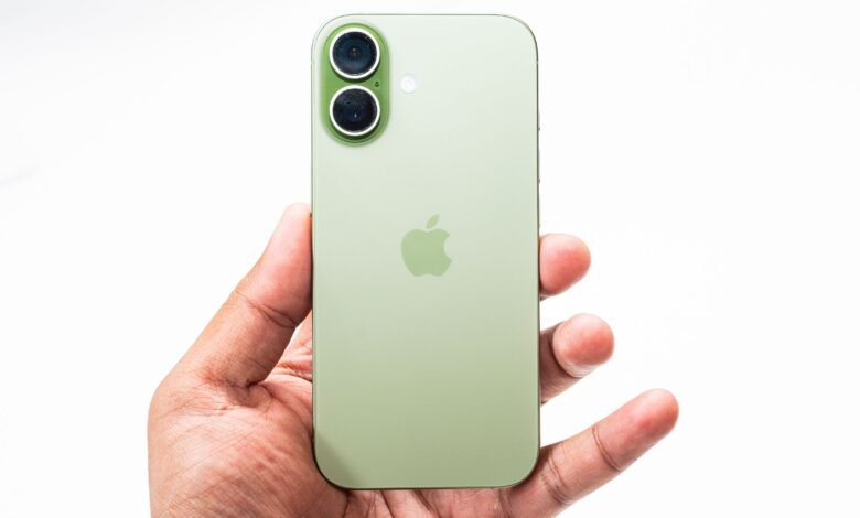 Close-up of a hand holding a sage green iPhone 17, showcasing its dual-lens camera and Apple logo.