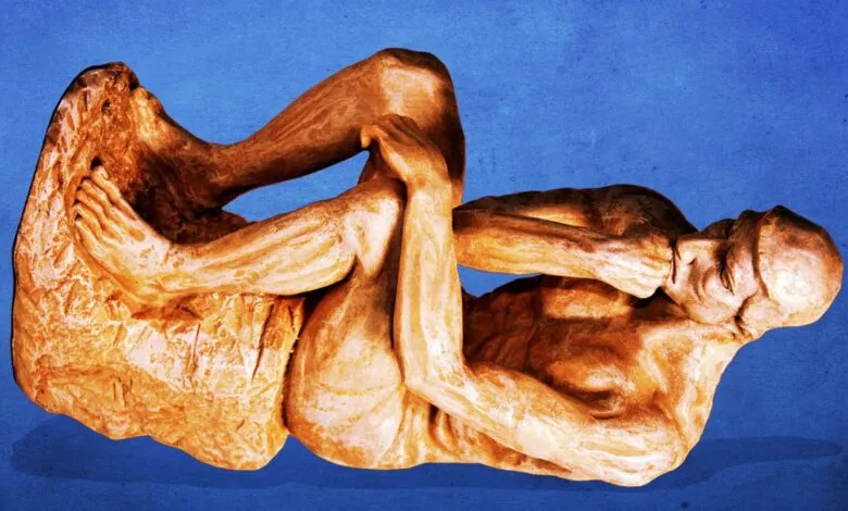 Bronze-toned statue of a man in a contemplative pose, reclining against a rock, set against a deep blue background.