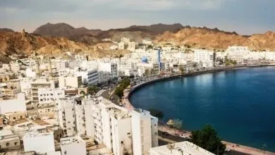 Aerial view of Mutrah, Oman, showing the coastline, buildings, and mountains.