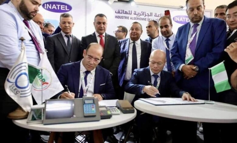 Businesspeople signing a contract at a conference, surrounded by colleagues.