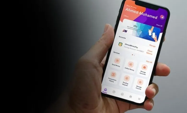 Hand holding smartphone displaying mobile banking app interface with account details and transaction options.